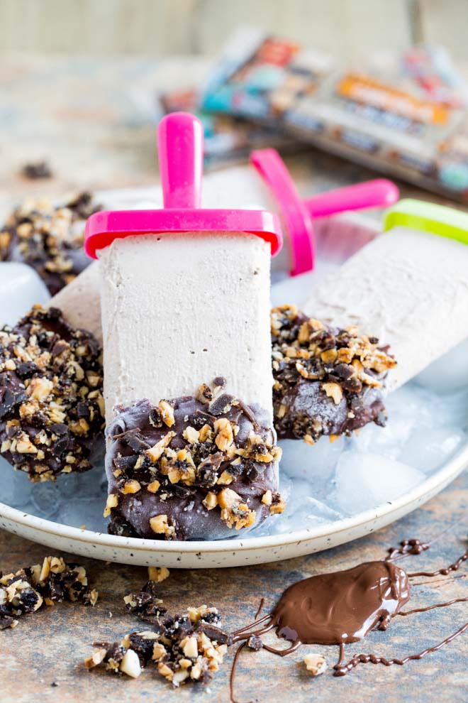 These vegan ice cream pops are smooth, creamy and super easy to make! We've also got vegan protein bars crushed into the ice cream and nibbly chunks on the rich chocolate coating. The perfect healthy summer treat! #veganrecipes #veganicecream #veganprotein #healthysnack | Recipe on thecookandhim.com