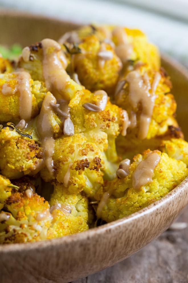 Gently spiced cauliflower cooked to crispy perfection! Drizzled with a smooth creamy tahini dressing this roasted cauliflower is easy and SO delicious! #roastedcauliflower #cauliflowerrecipes #veganrecipes #plantbased | Recipe on thecookandhim.com