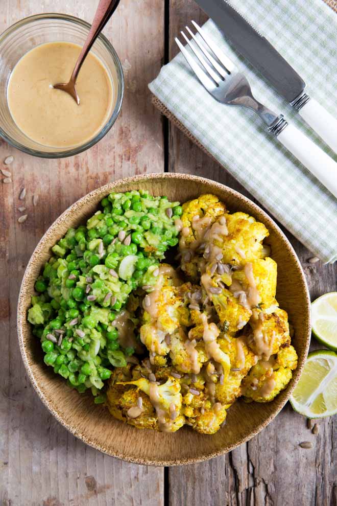 Gently spiced cauliflower cooked to crispy perfection! Drizzled with a smooth creamy tahini dressing this roasted cauliflower is easy and SO delicious! #roastedcauliflower #cauliflowerrecipes #veganrecipes #plantbased | Recipe on thecookandhim.com