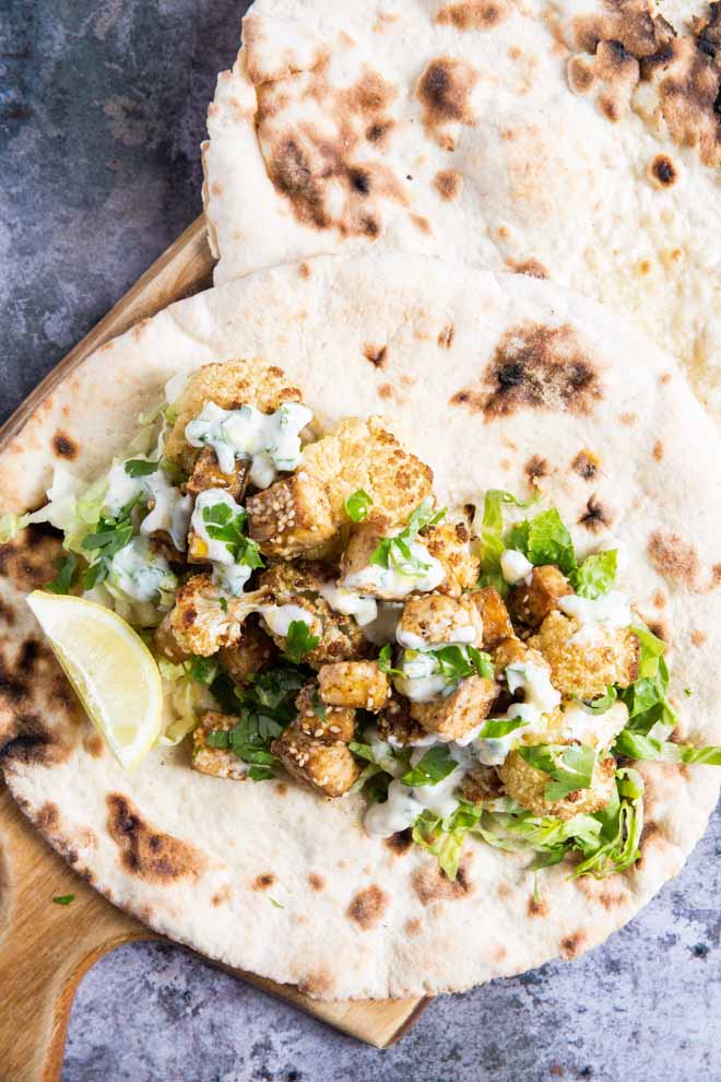 Crispy baked za'atar tofu and cauliflower, gently spiced and full of flavour. Drizzle with a creamy vegan tzatziki sauce for a quick and easy weeknight meal! #tofurecipes #cauliflowerrecipes #veganrecipes #veganmeal | Recipe on thecookandhim.com