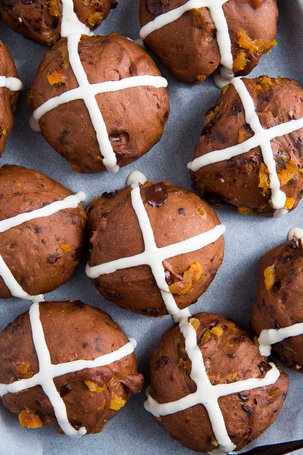 Celebrate Easter in style with these heavenly Double Chocolate and Orange Hot Cross Buns! Packed with zesty orange, chocolate chunks and soft apricots! #veganeaster #easterrecipes #veganchocolate #veganbaking #hotcrossbuns | Recipe on thecookandhim.com