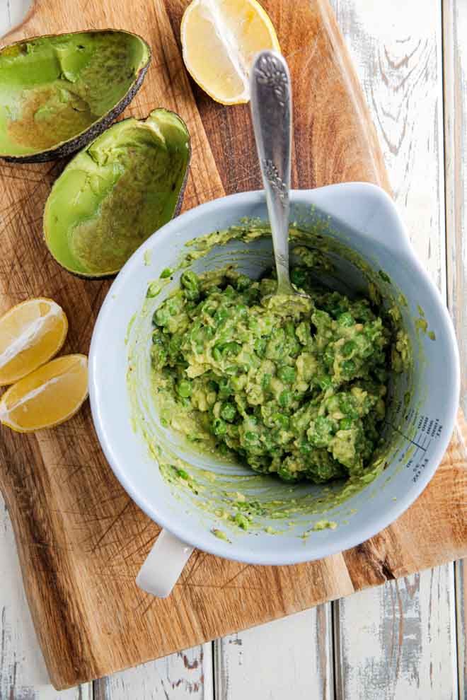 Bright petit pois and fresh herbs liven up a traditional guacamole, giving it a lovely sweetness and chunky texture, perfect for dipping and spreading! #healthyfats #mexicanfood #guacamole #avocadorecipes #avocado #avocadodip #veganguacamole #dip | Recipe on thecookandhim.com