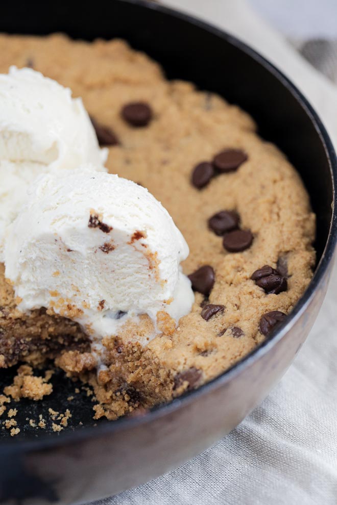 Warm, gooey and delicious this vegan chocolate chip skillet cookie is easily made in advance, baked fresh and a real crowd favourite! #skilletcookie #vegancookie #pizookie #veganrecipes #veganbaking #dairyfree | Reipe on thecookandhim.com