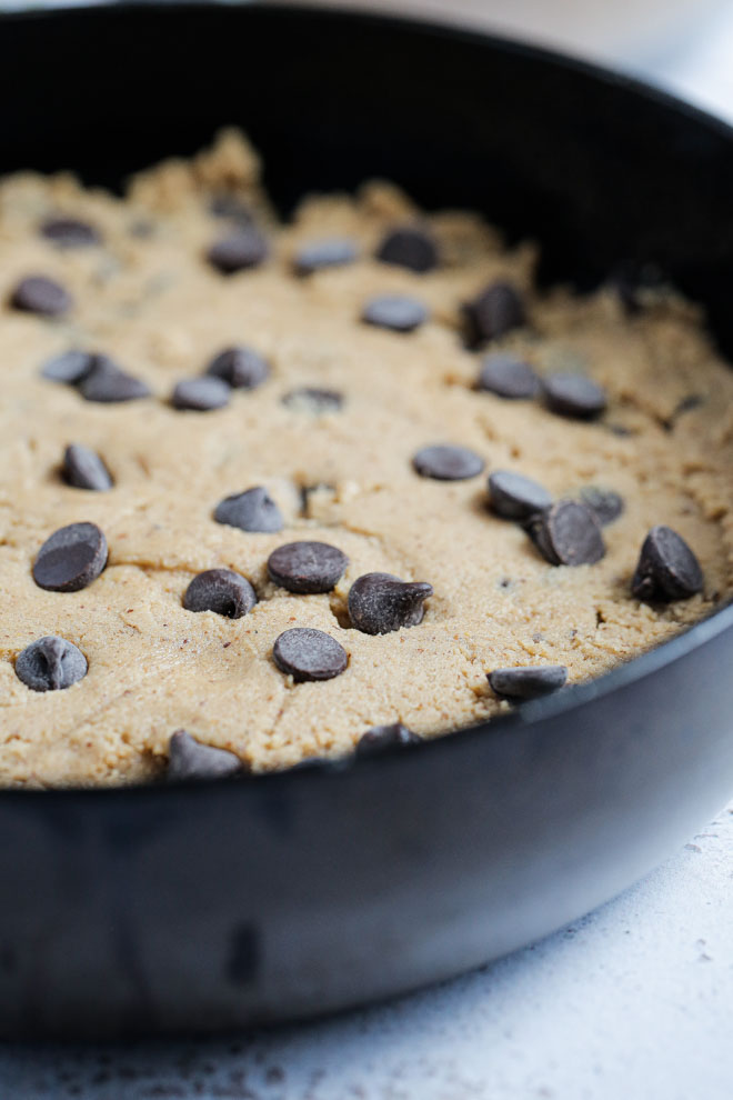 Warm, gooey and delicious this vegan chocolate chip skillet cookie is easily made in advance, baked fresh and a real crowd favourite! #skilletcookie #vegancookie #pizookie #veganrecipes #veganbaking #dairyfree | Reipe on thecookandhim.com
