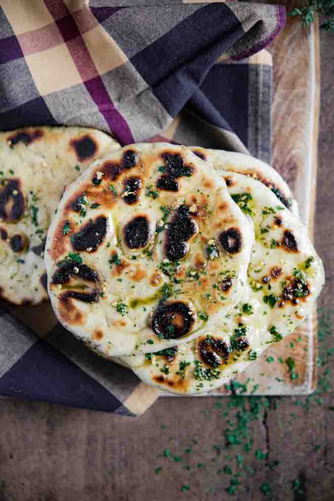 Even if you've never made bread at home before, this soft, chewy naan bread is a great place to start! There are no complicated ingredients and no furious kneading of dough - just mix, prove and cook. Oh and plenty of garlic and herb butter! #naan #vegannaan #naanbread #bread #yeast #homemade #flatbread #easynaanbread #garlicnaan #plantbased | Recipe on thecookandhim.com