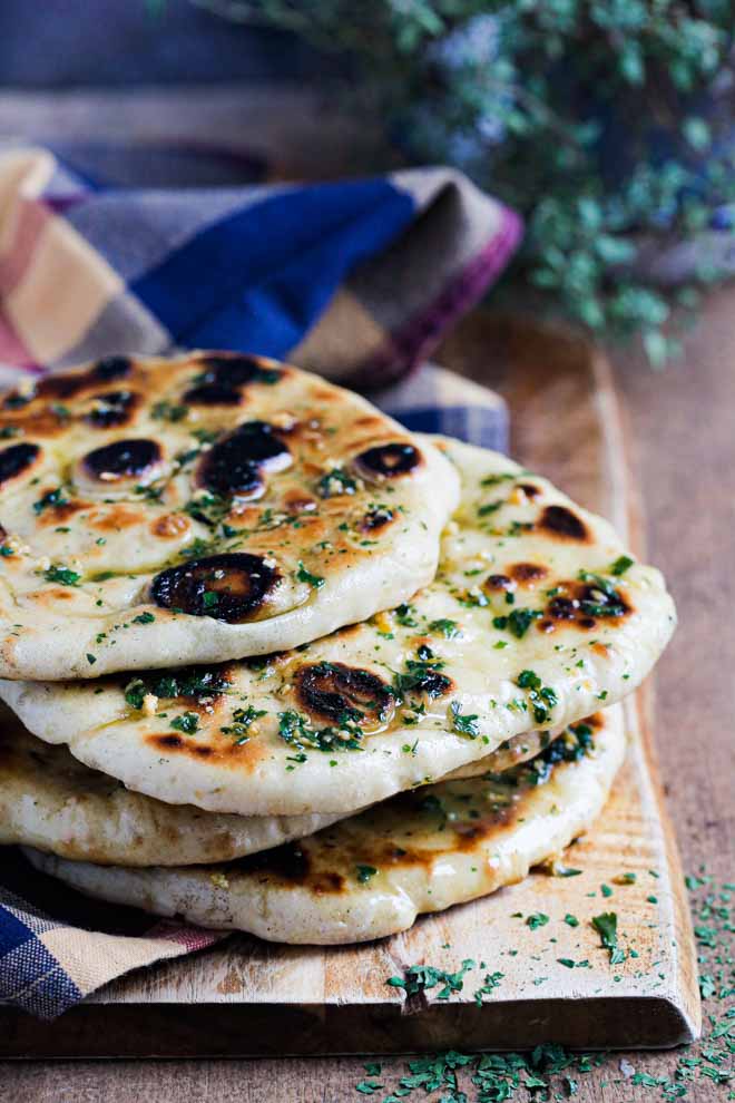 Even if you've never made bread at home before, this soft, chewy naan bread is a great place to start! There are no complicated ingredients and no furious kneading of dough - just mix, prove and cook. Oh and plenty of garlic and herb butter! #naan #vegannaan #naanbread #bread #yeast #homemade #flatbread #easynaanbread #garlicnaan #plantbased | Recipe on thecookandhim.com