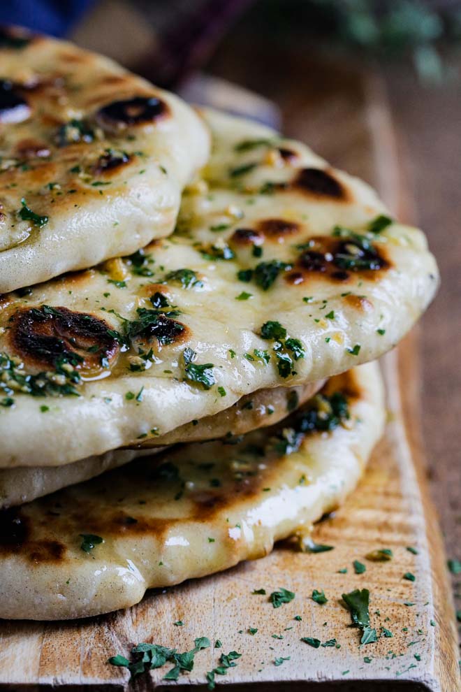 Even if you've never made bread at home before, this soft, chewy naan bread is a great place to start! There are no complicated ingredients and no furious kneading of dough - just mix, prove and cook. Oh and plenty of garlic and herb butter! #naan #vegannaan #naanbread #bread #yeast #homemade #flatbread #easynaanbread #garlicnaan #plantbased | Recipe on thecookandhim.com