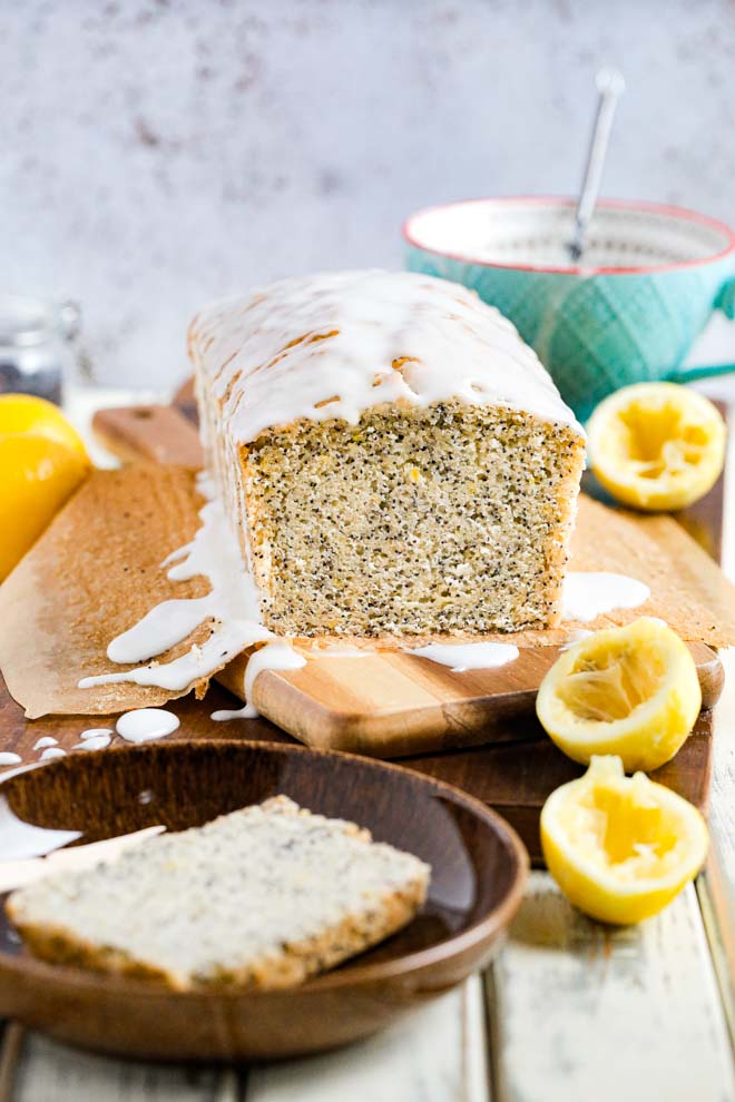 Zingy lemons and light poppy seeds combine perfectly in this delicate but moist vegan lemon poppy seed cake. Topped with a drizzle of sweet icing you'll be making this cake again and again! #lemoncake #lemonpoppyseedcake #lemonloaf #vegancake #dairyfree #eggfreecake #veganbaking #nondairymilk #veganmilk | Recipe on thecookandhim.com