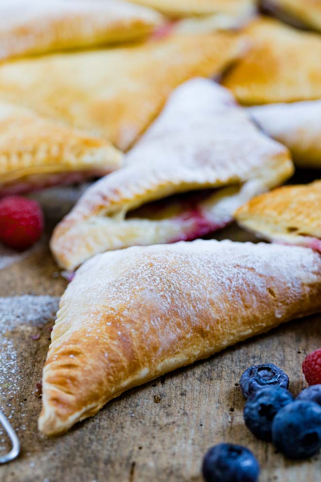 Crisp puff pastry filled with passion fruit flavour vegan cream cheese makes these berry breakfast pastries a simple but decadent crowd pleaser! Glaze with demerara sugar or icing sugar for a super simple sweet treat! #breakfastpastries #veganbreakfast #passionfruit #turnovers #vegancheese #vegandanish #puffpastry | Recipe on thecookandhim.com