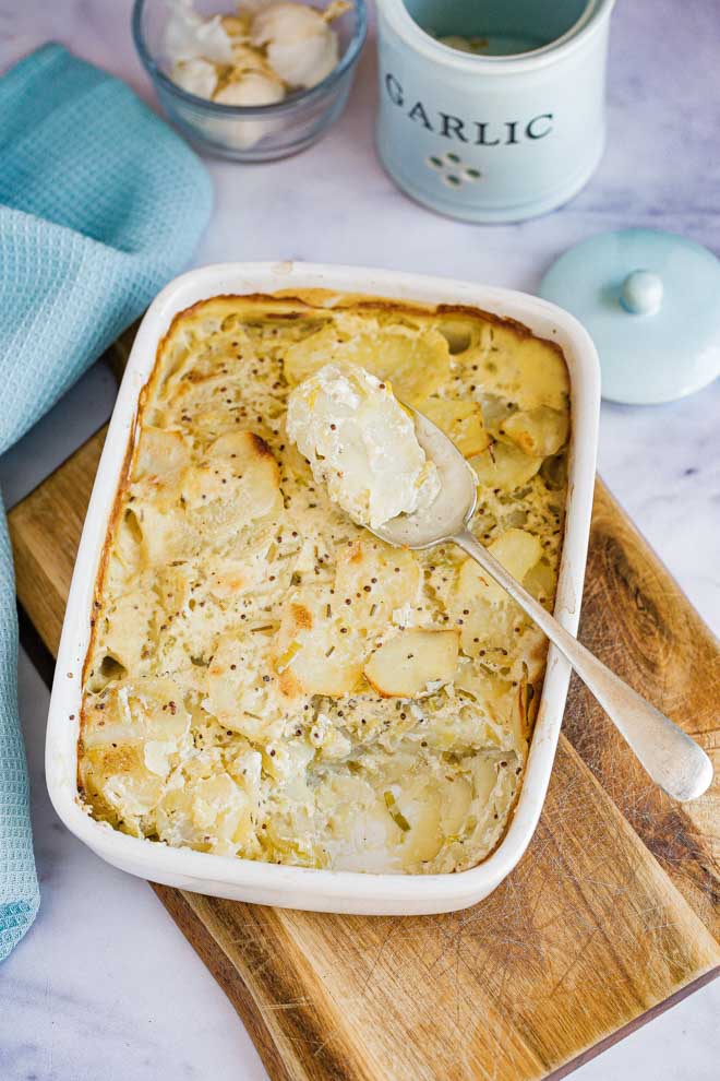 Layers of leek and potato with a rich garlic, rosemary and mustard cream sauce takes these vegan dauphinoise from delicious to extraordinary! So simple to make and so satisfying to eat! #veganside #scallopedpotatoes #veganscallopedpotatoes #veganpotatodish #vegandauphinoise #glutenfree #vegan #veganrecipes #dairyfree #plantbased | Recipe on thecookandhim.com