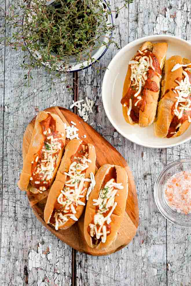 Crusty rolls stuffed with BBQ meatballs, smothered in a tangy homemade tomato sauce and topped with vegan cheese for a family favourite! #veganbbq #vegansubs #veganrecipes #veganmeatballs #meatfree #plantbased #meatlessmeatballs | Recipe on thecookandhim.com