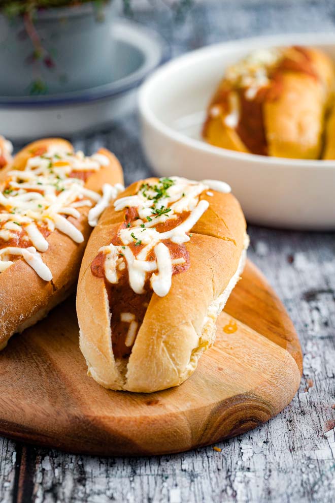 Crusty rolls stuffed with BBQ meatballs, smothered in a tangy homemade tomato sauce and topped with vegan cheese for a family favourite! #veganbbq #vegansubs #veganrecipes #veganmeatballs #meatfree #plantbased #meatlessmeatballs | Recipe on thecookandhim.com