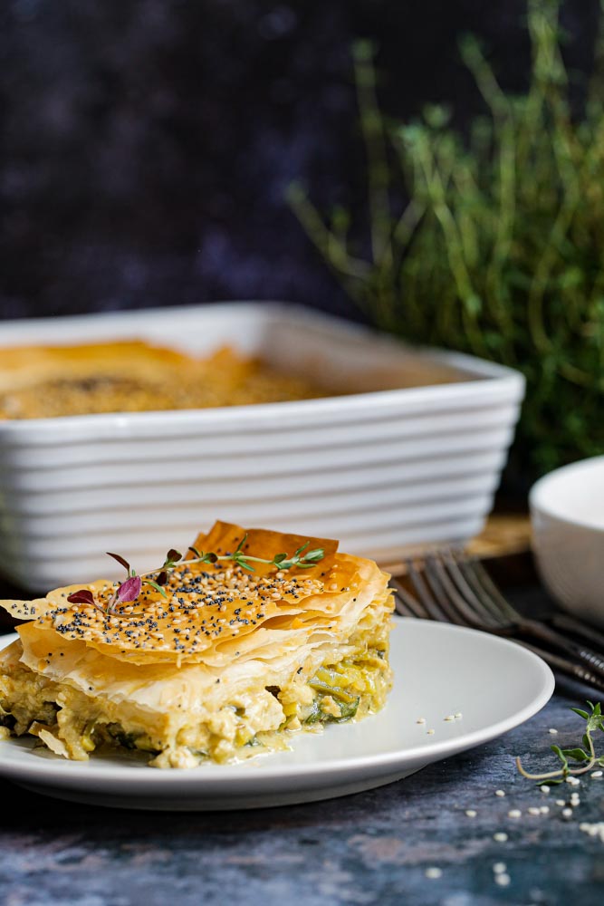 Crisp, ruffled pastry tops this filo pie. Packed with creamy leeks, spinach, black garlic and tofu as well as rich, hearty flavours! This pie is a great vegan roast dinner alternative, is easy to prepare and can be served with anything from roast veggies to a simple seasonal salad for a truly versatile meal! Recipe on thecookandhim.com #filo #filorecipes #filopastry #vegan #veganpie #vegandinnerideas #veganchristmas