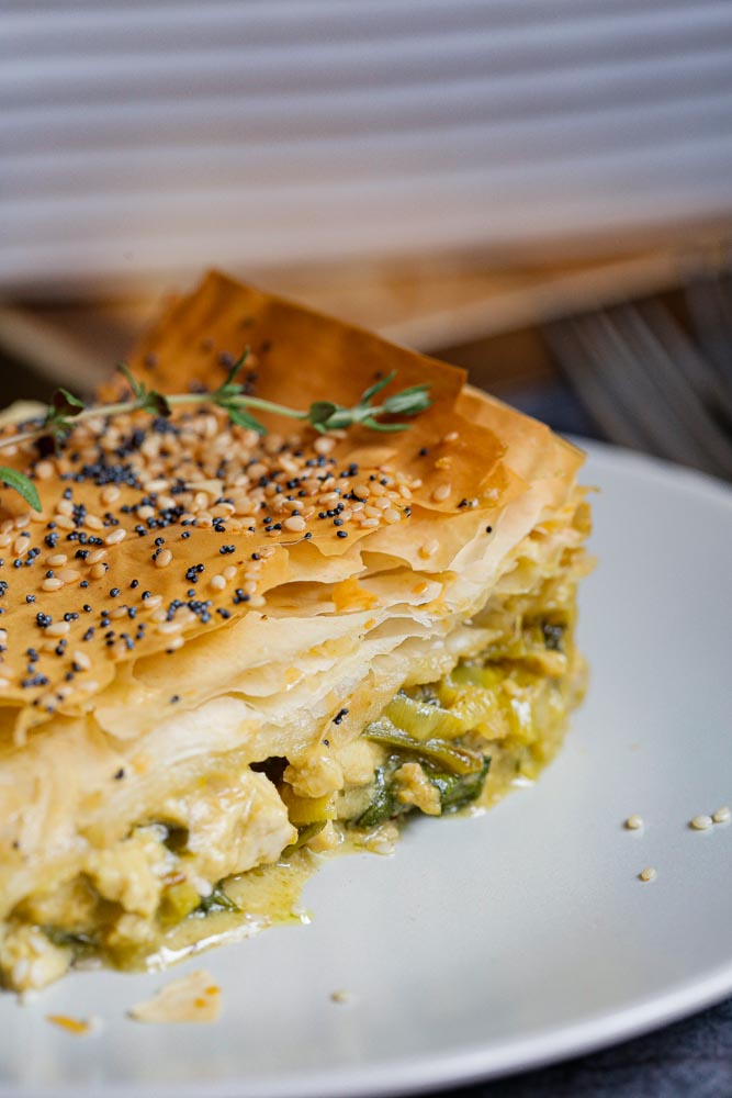 Crisp, ruffled pastry tops this filo pie. Packed with creamy leeks, spinach, black garlic and tofu as well as rich, hearty flavours! This pie is a great vegan roast dinner alternative, is easy to prepare and can be served with anything from roast veggies to a simple seasonal salad for a truly versatile meal! Recipe on thecookandhim.com #filo #filorecipes #filopastry #vegan #veganpie #vegandinnerideas #veganchristmas