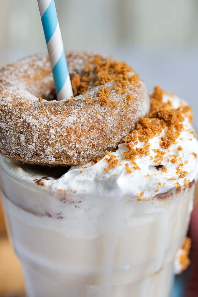 Rich and decadent this vegan banana and biscoff freakshake is a dessert in a glass! The base recipe is so simple and quick to whip up with just 5 ingredients, then top with homemade baked donuts and whipped cream for a deliciously extravagant sweet treat! Recipe on thecookandhim.com #freakshake #veganmilk #veganfreakshake #dairyfree #milkshake #biscoff #veganmilkshake #lotusbiscoff