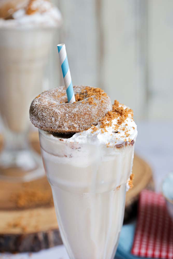 Rich and decadent this vegan banana and biscoff freakshake is a dessert in a glass! The base recipe is so simple and quick to whip up with just 5 ingredients, then top with homemade baked donuts and whipped cream for a deliciously extravagant sweet treat! Recipe on thecookandhim.com #freakshake #veganmilk #veganfreakshake #dairyfree #milkshake #biscoff #veganmilkshake #lotusbiscoff