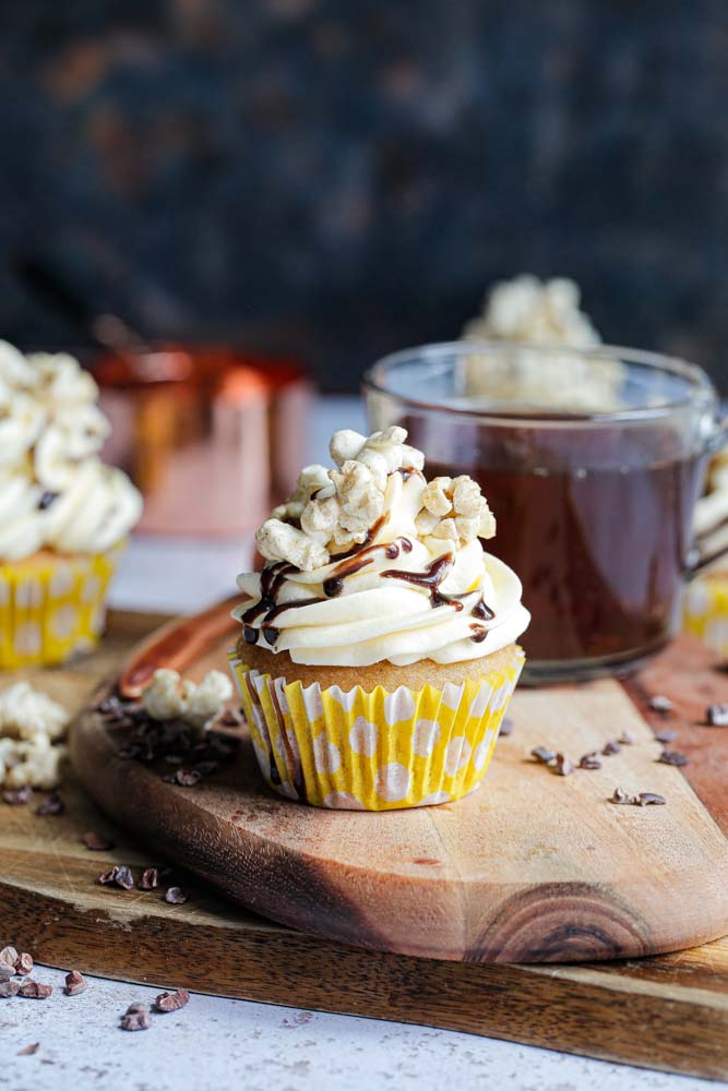 Full of buttery caramel flavour in both the deliciously soft sponge and fluffy buttercream frosting these cupcakes are perfect for both beginner and expert vegan bakers! They make a wonderful afternoon treat or autumn picnic dessert! Top with salted caramel popcorn and chocolate drizzle for real indulgence! | Recipe on thecookandhim.com #caramelcupcakes #saltedcaramel #cupcakes #vegancupcakes #veganbaking #veganbuttercream #veganrecipes #autumnrecipes #fallrecipes