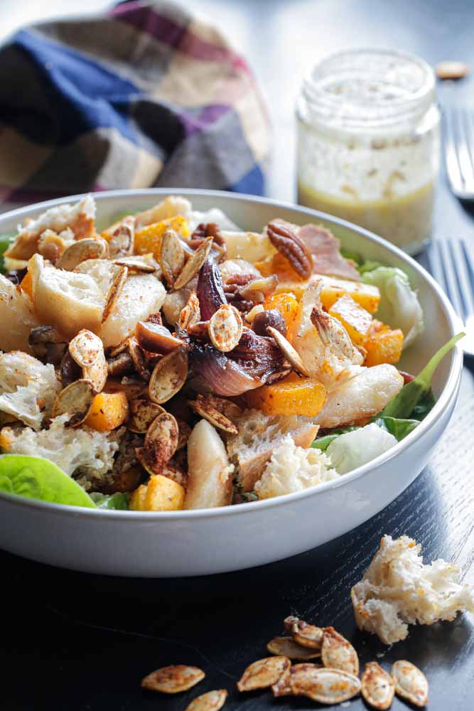 Drizzled with a light tahini dressing this fully loaded pumpkin salad with warm pears, toasted pecans, crisp croutons and spiced pumpkin seeds is everything a salad should be! Recipe on thecookandhim.com #roastedpumpkin #pumpkinrecipes #pumpkinsalad #vegan #tahini #roastedvegsalad #warmsalad