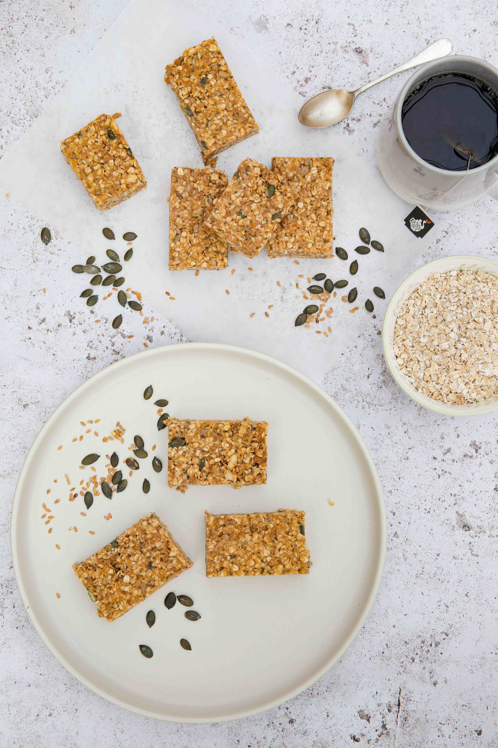 EASY no bake homemade peanut butter oat bars - full of seeds, nuts and dried fruits. Refined sugar free but sweet and chewy and perfect for a quick breakfast or snack! Vegan and gluten free recipe on thecookandhim.com #nobakebars #peanutbutterbars #granolabars