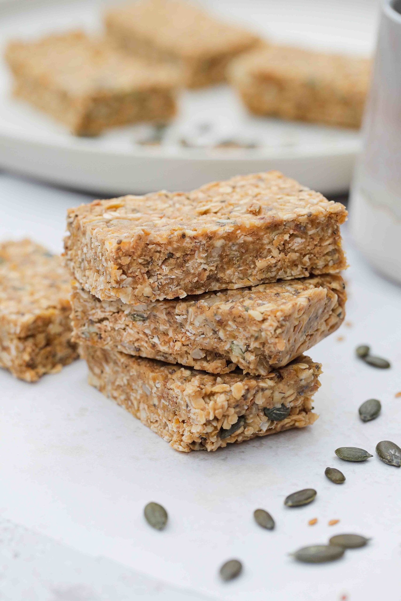 EASY no bake homemade peanut butter oat bars - full of seeds, nuts and dried fruits. Refined sugar free but sweet and chewy and perfect for a quick breakfast or snack! Vegan and gluten free recipe on thecookandhim.com #nobakebars #peanutbutterbars #granolabars