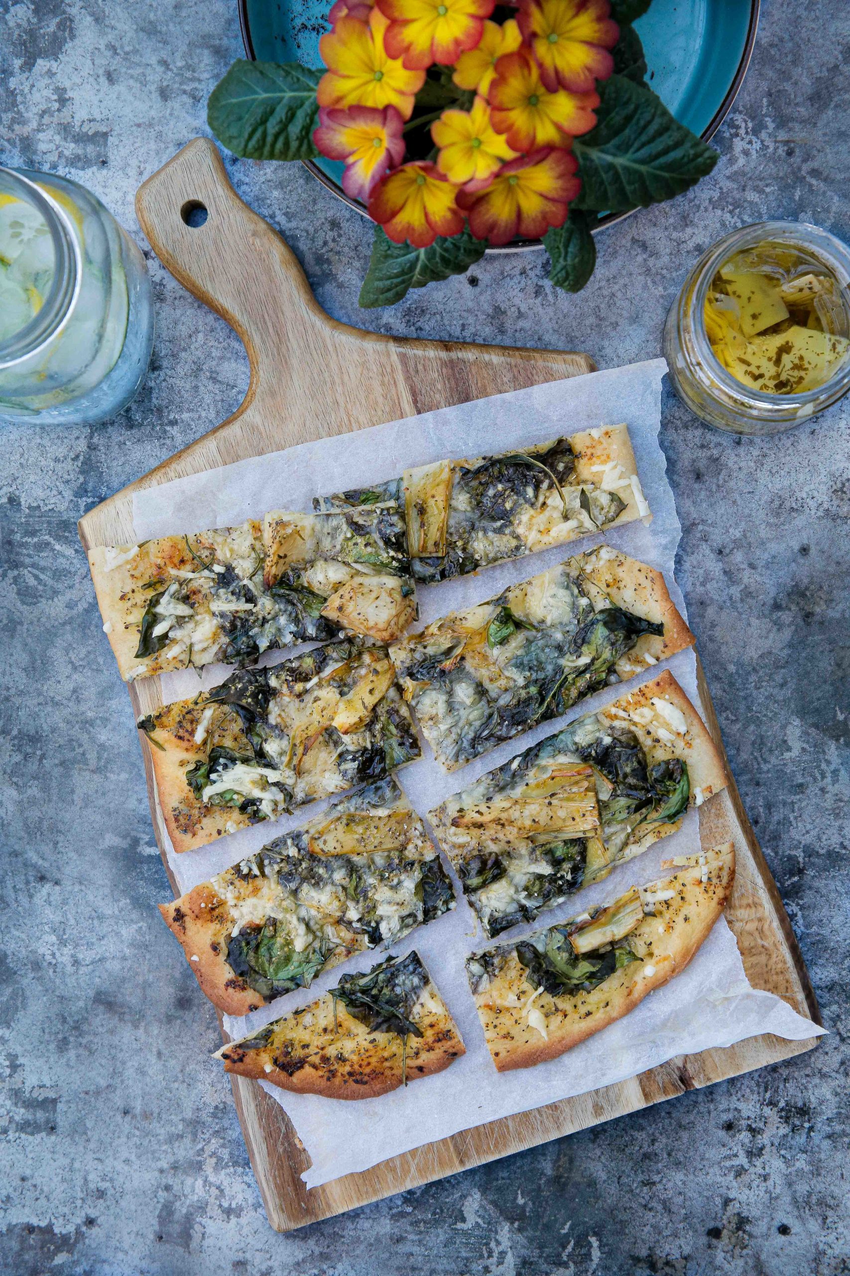 Garlicky, herby and cheesy this vegan spinach and artichoke pizza is so easy to make, so much cheaper than takeaway and beyond delicious! Recipe on thecookandhim.com #veganpizza #pizzarecipe #homemadepizza