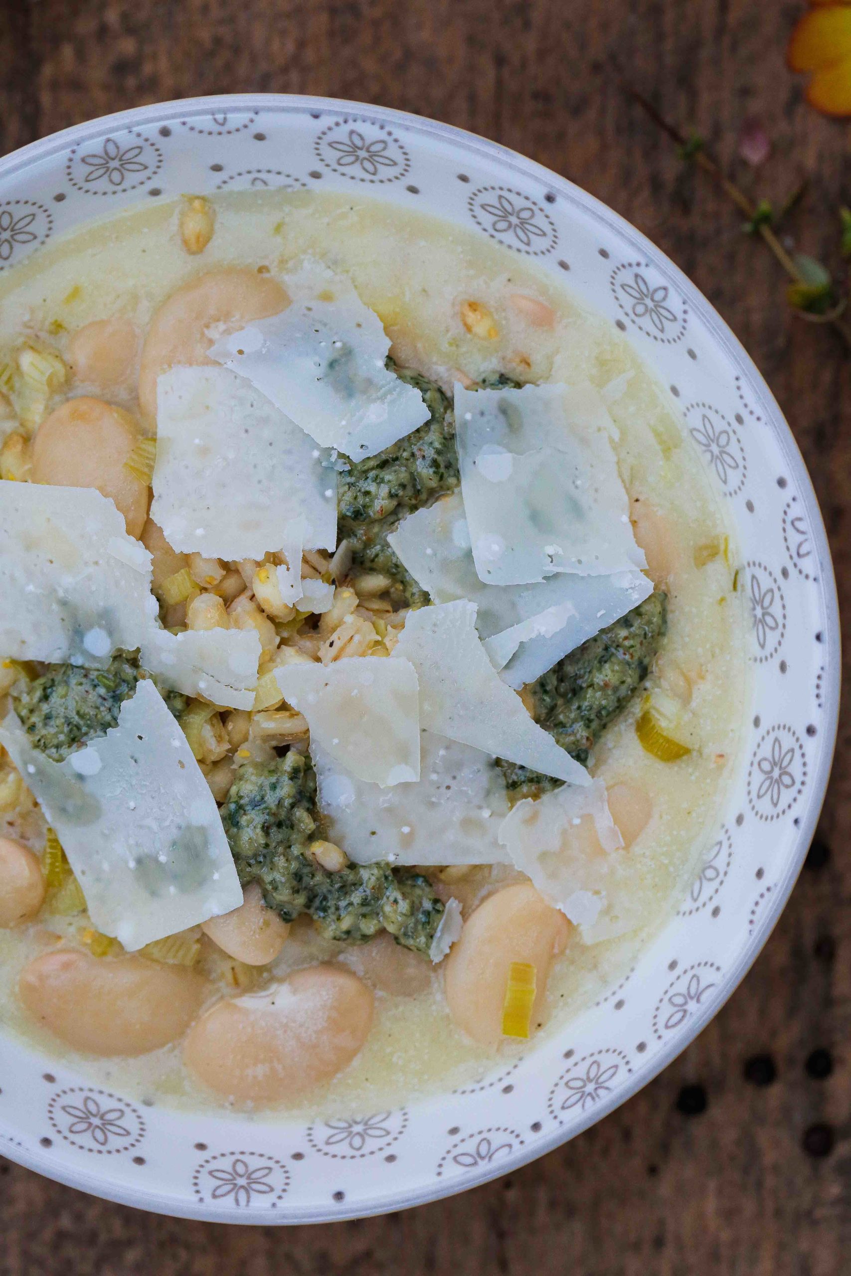 This rich and creamy white bean soup with leeks, pearl barley and pesto is so easy to make - just one pan needed - and full of hearty delicious flavours! Recipe on thecookandhim.com #vegansoup #whitebeansoup #vegansouprecipe