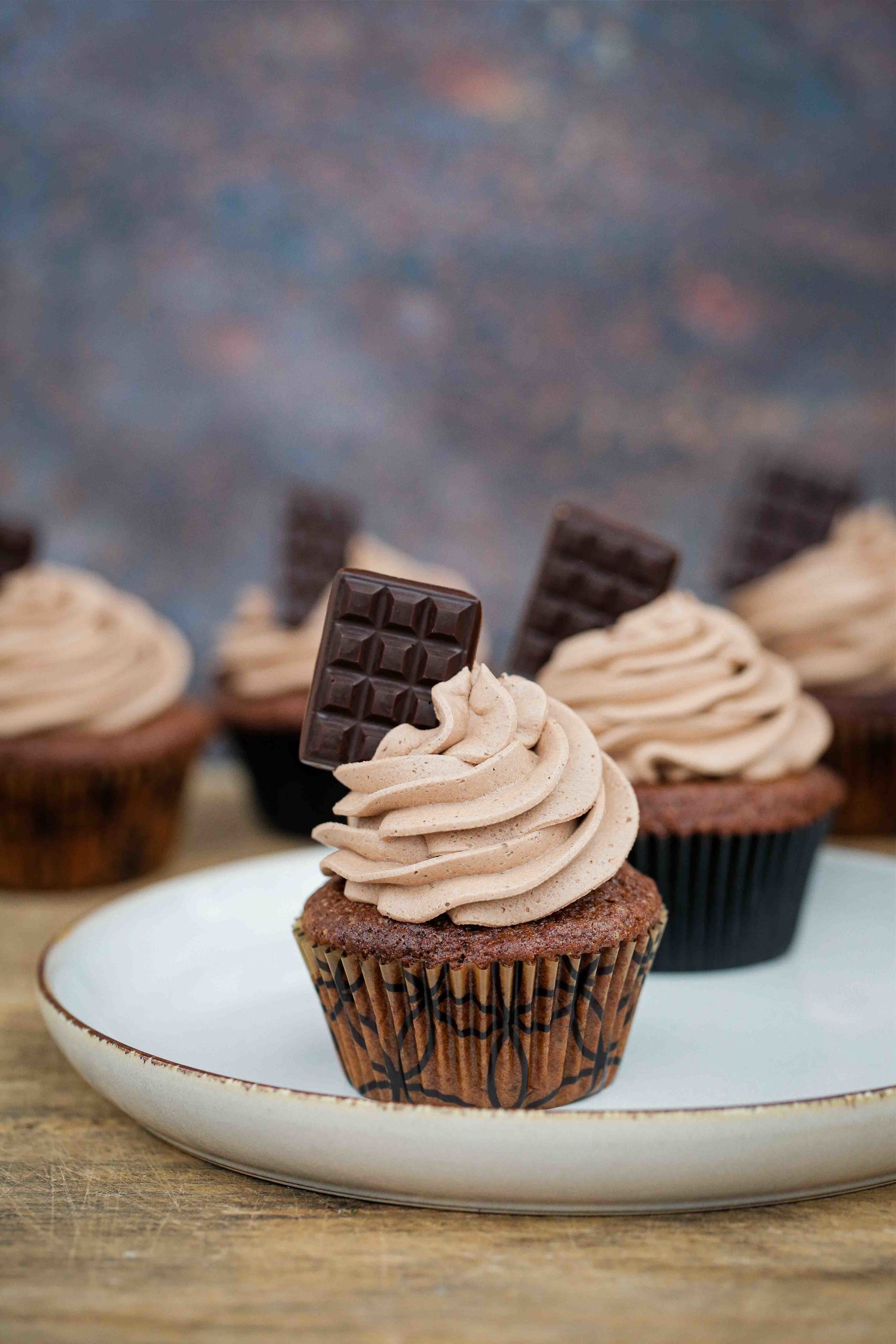 Warming chai spices are blended into these vegan chocolate cupcakes. Top with a fluffy chocolate buttercream for a delightful afternoon treat! Recipe on thecookandhim.com #vegancupcakes #buttercream #chaispice #chailatte #chocolatecupcakes