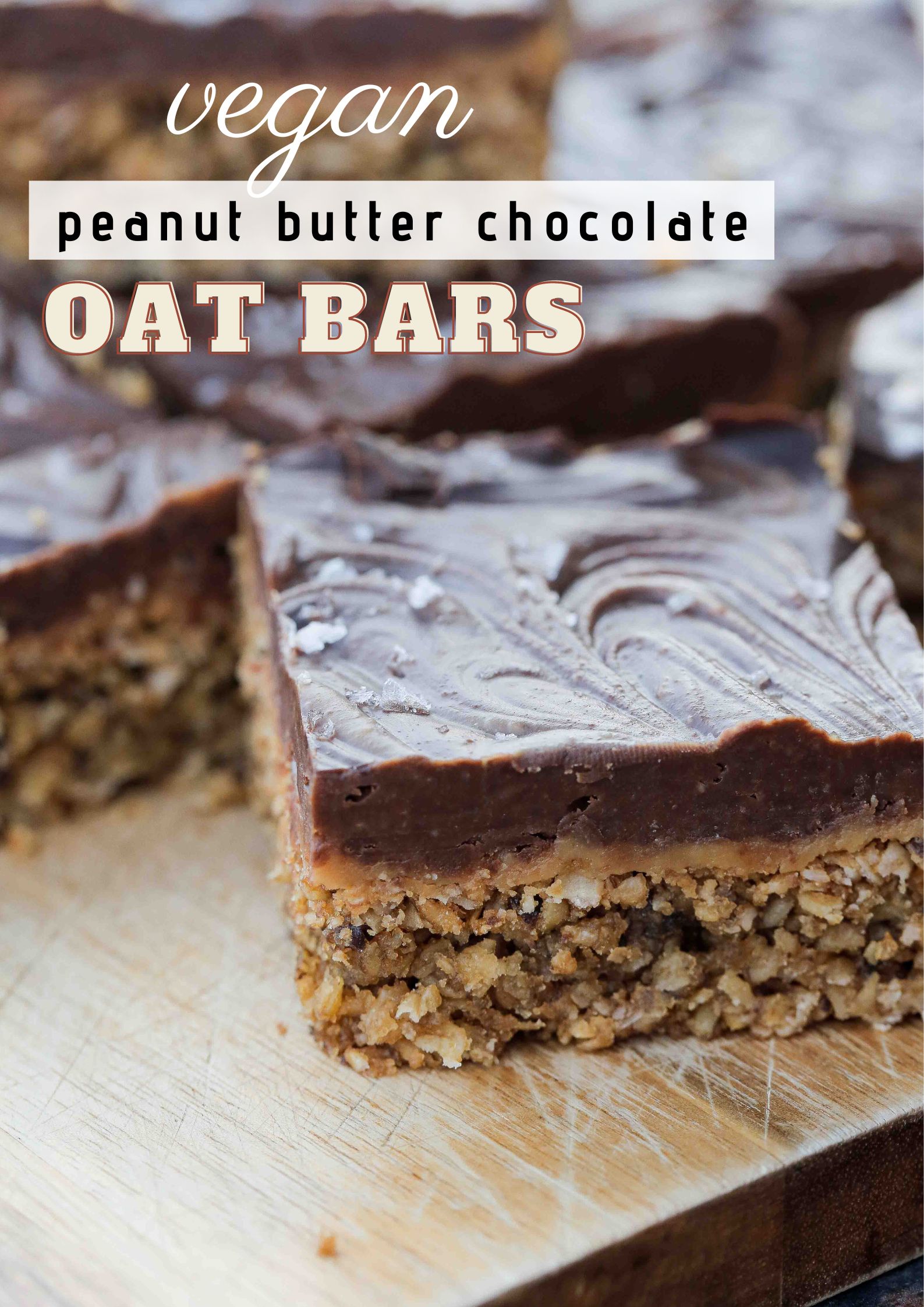 Delicious vegan dark chocolate oatmeal bars with a layer of creamy peanut butter and a sprinkle of sea salt. The oatmeal cookie base is sweet, buttery and cooked to chewy perfection! Recipe on thecookandhim.com #peanutbutterchocolateoatmealbars #oatmealcookiebars #chocolateoatbars #veganbaking #veganrecipes