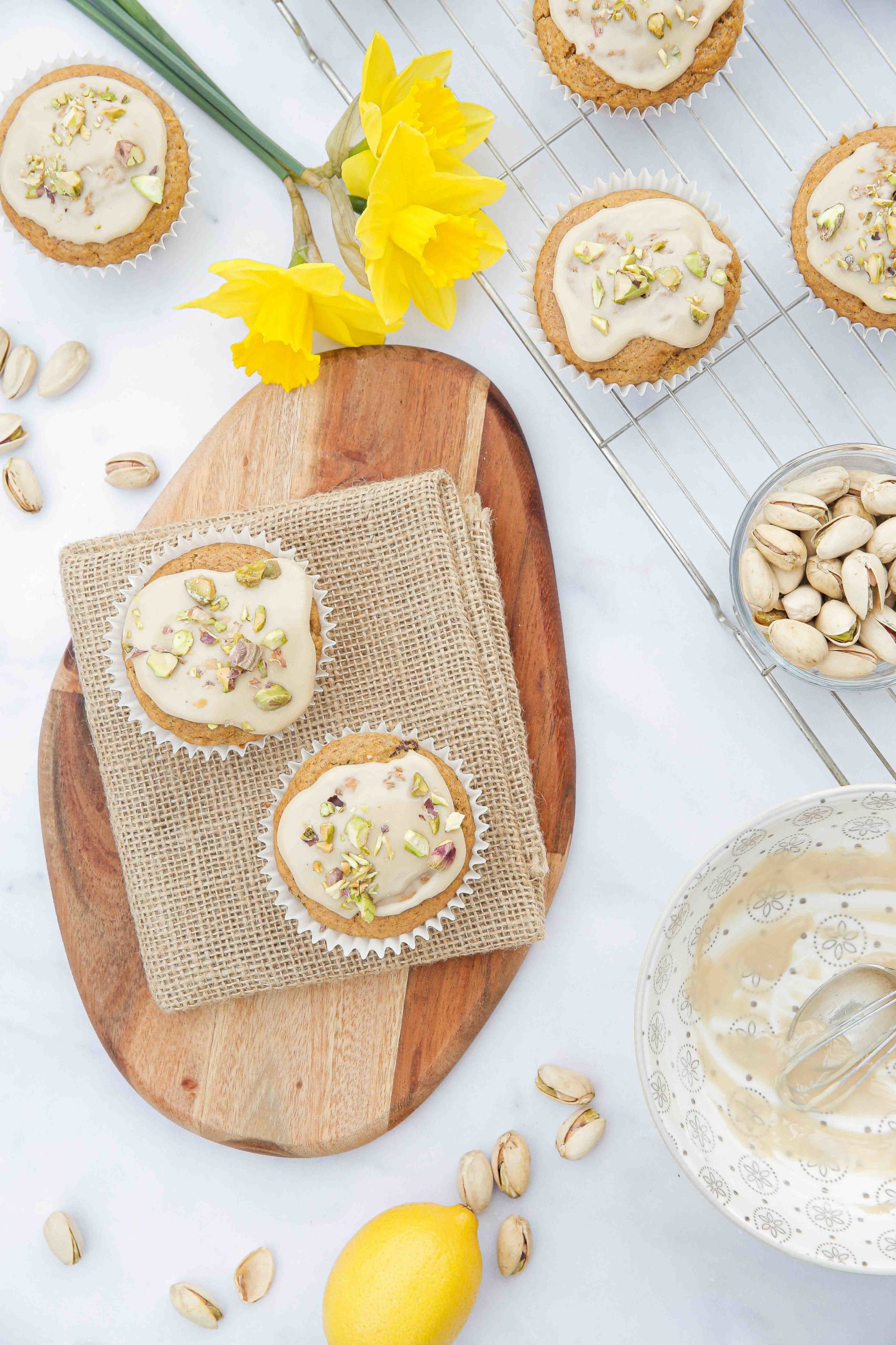 Delicious and super easy vegan carrot cake muffins with all the spice and flavour of carrot cake just in a more portable form! Topped with a lovely lemon icing and chopped pistachios. Enjoy with your morning coffee or as an afternoon treat. Recipe on thecookandhim.com | #carrotmuffins #carrotcakemuffins #muffinrecipe #veganmuffins #snack #vegansnacks