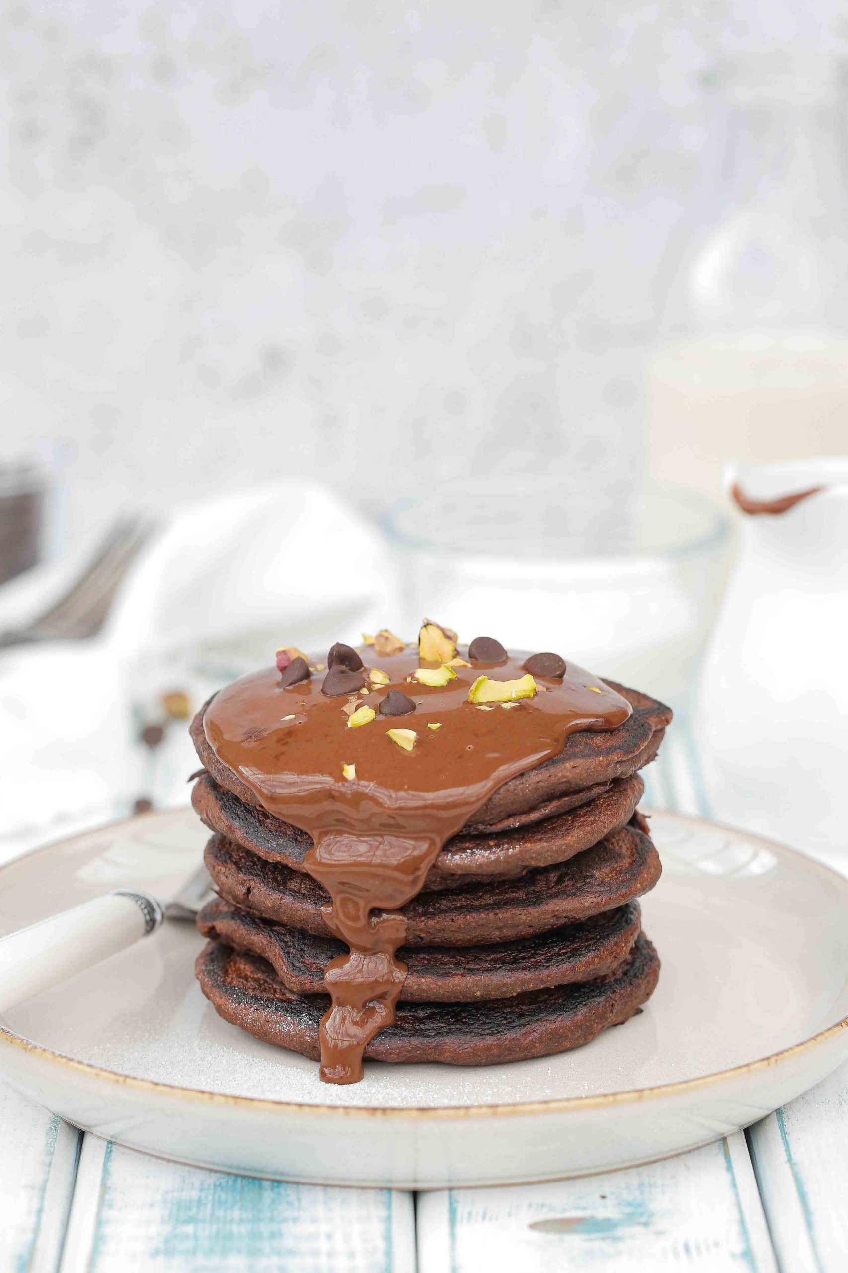 These easy vegan and gluten free chocolate pancakes are a chocolate lovers dream! Fluffy, full of rich cacao flavour and made with simple ingredients - including the divine chocolate sauce! Recipe on thecookandhim.com | #veganpancakes #veganbreakfast #chocolatepancakes #veganrecipes #glutenfree