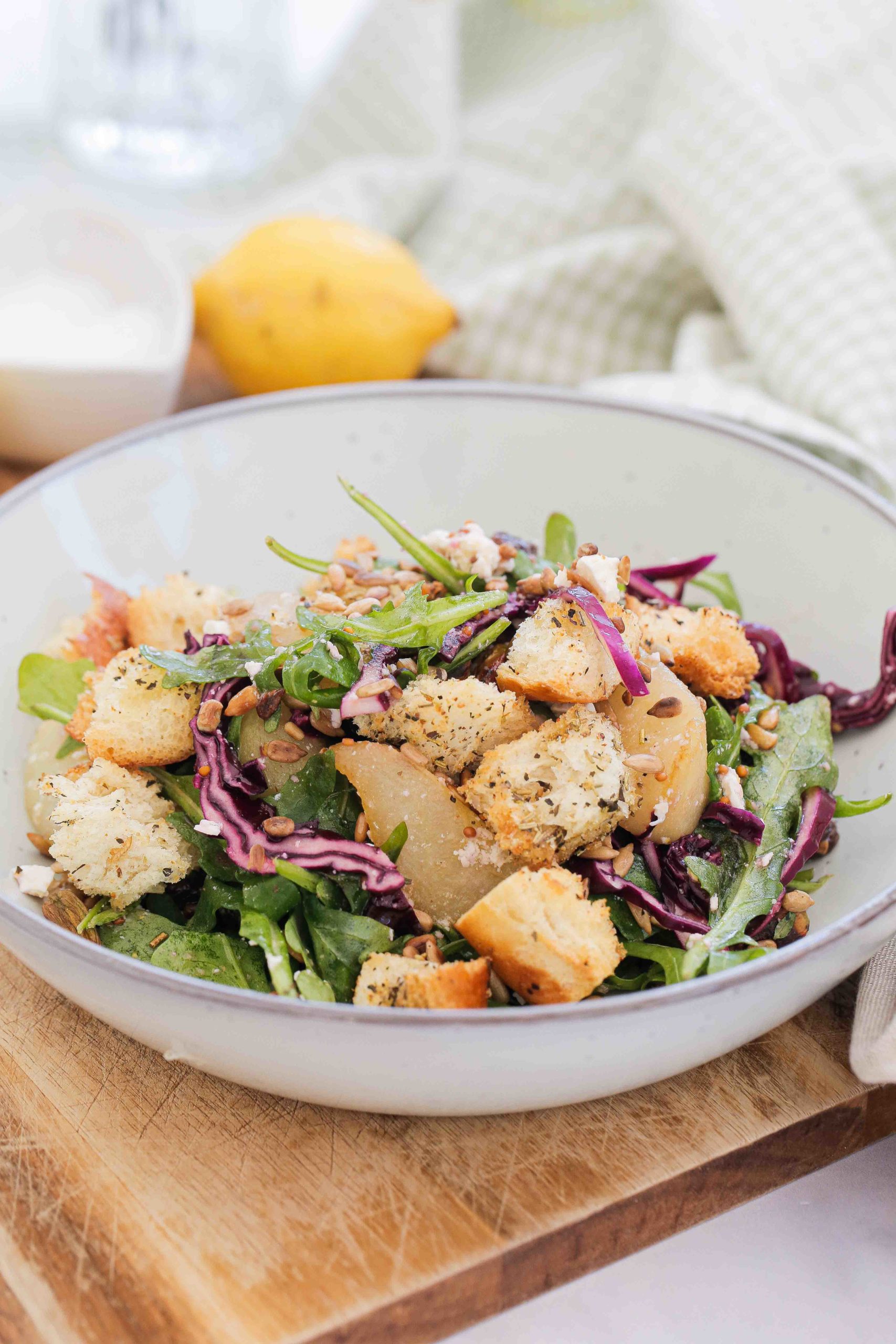 This pear salad will easily become a seasonal favourite! Made with roasted pears, red cabbage, homemade croutons and a tangy mustard dressing. Recipe on thecookandhim.com #pearsalad #redcabbage #arugula #rocket #stalebread #homemadecroutons