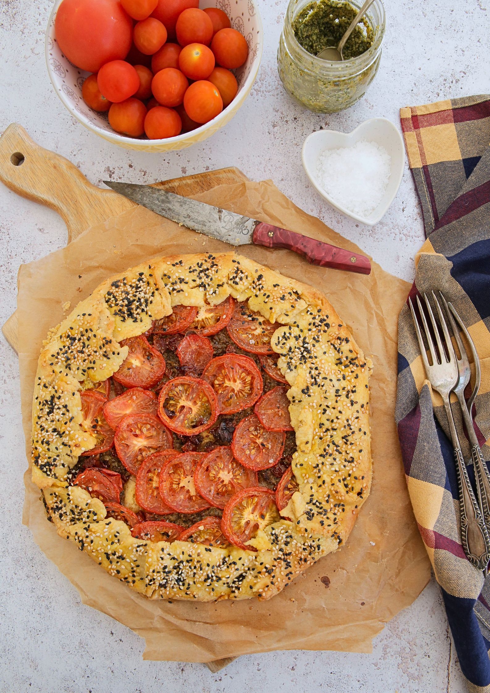 Crisp, flaky, buttery pastry, homemade pesto and sweet summer tomatoes make the perfect rustic tomato galette. This is so simple to put together but SO full of flavour! Recipe on thecookandhim.com | #tomatogalette #tomatotart #easysummerrecipes #tomatoes #tomatorecipes #vegan #pesto