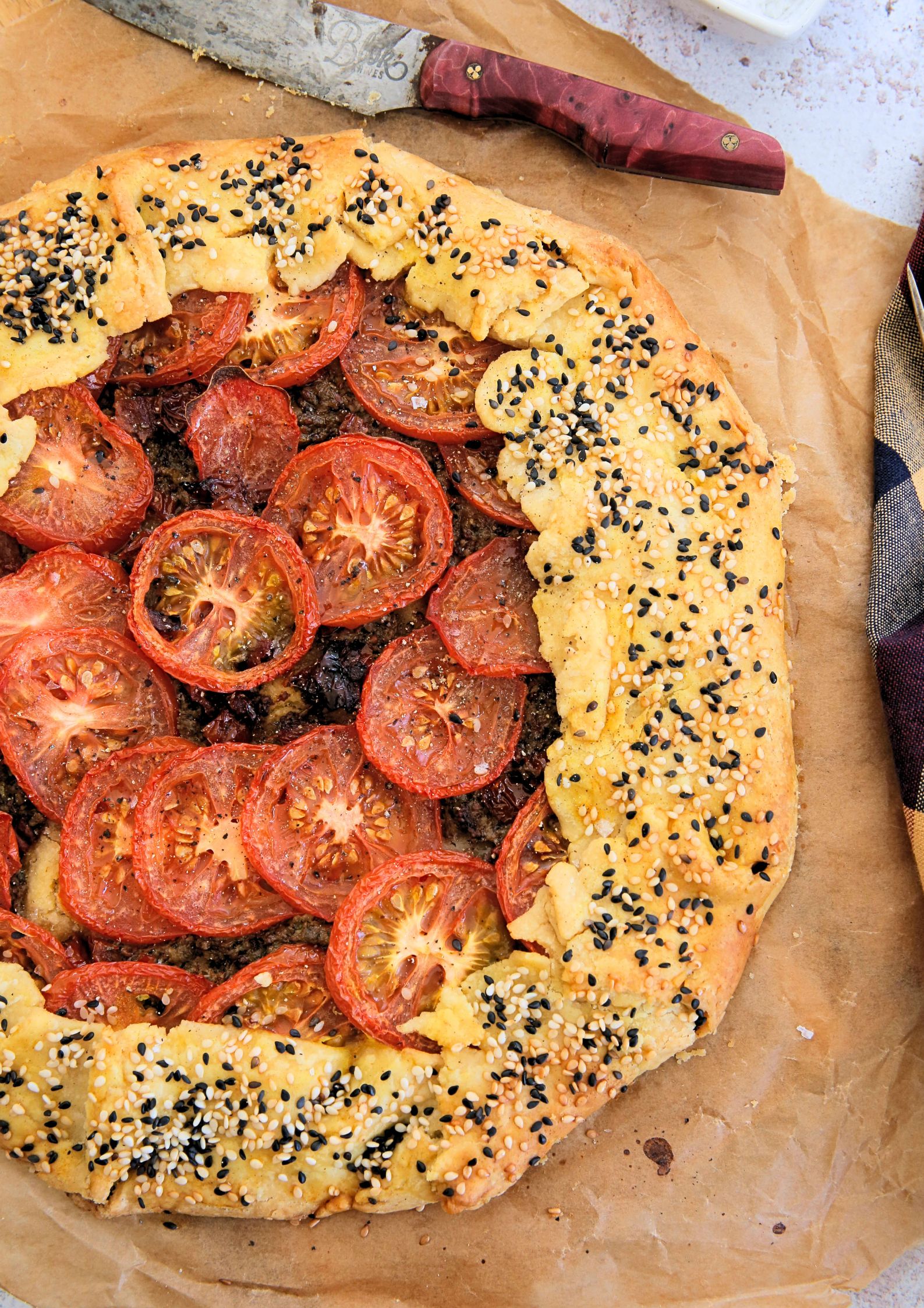 Crisp, flaky, buttery pastry, homemade pesto and sweet summer tomatoes make the perfect rustic tomato galette. This is so simple to put together but SO full of flavour! Recipe on thecookandhim.com | #tomatogalette #tomatotart #easysummerrecipes #tomatoes #tomatorecipes #vegan #pesto