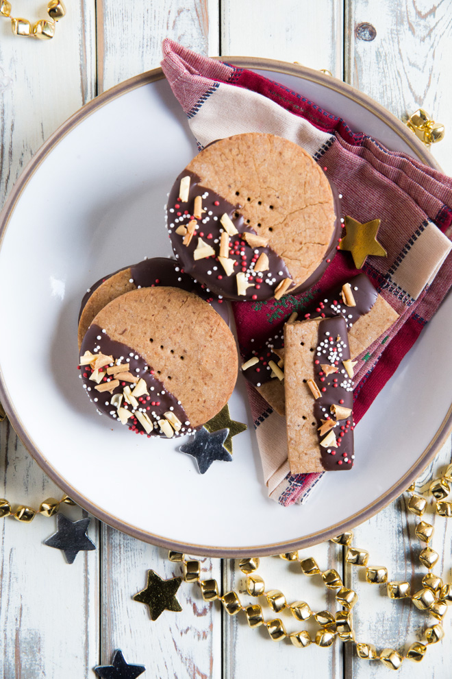 Baked with almond butter and warming festive spices these easy Christmas cookies are half dipped in chocolate for an extra special treat! Recipe on thecookandhim.com | #christmascookies #spicedcookies #veganchristmas #veganshortbread