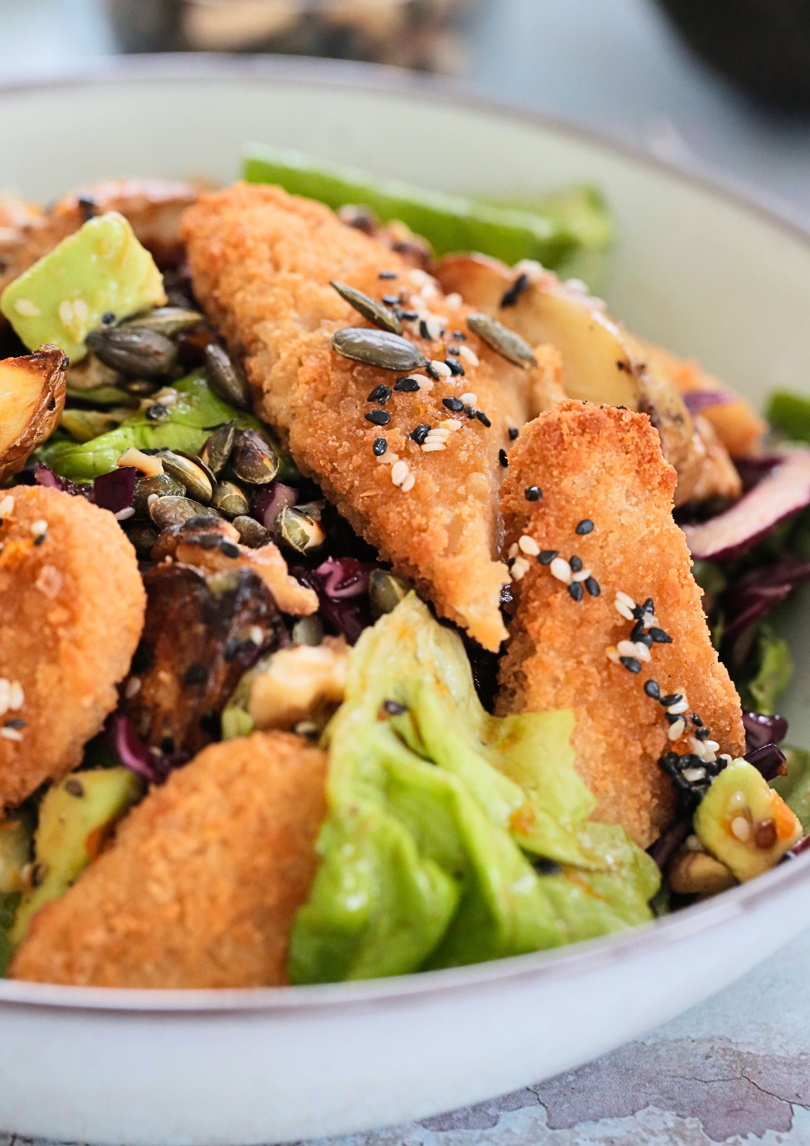 A warm winter salad recipe with crunchy fresh veggies, plant based chicken tenders and a spiced sesame orange salad dressing. A totally delicious but easy vegan lunch idea. Recipe on thecookandhim.com | #vegansaladrecipes #vegansaladdressing #saladrecipes #meatlessmeal #plantbasedrecipes