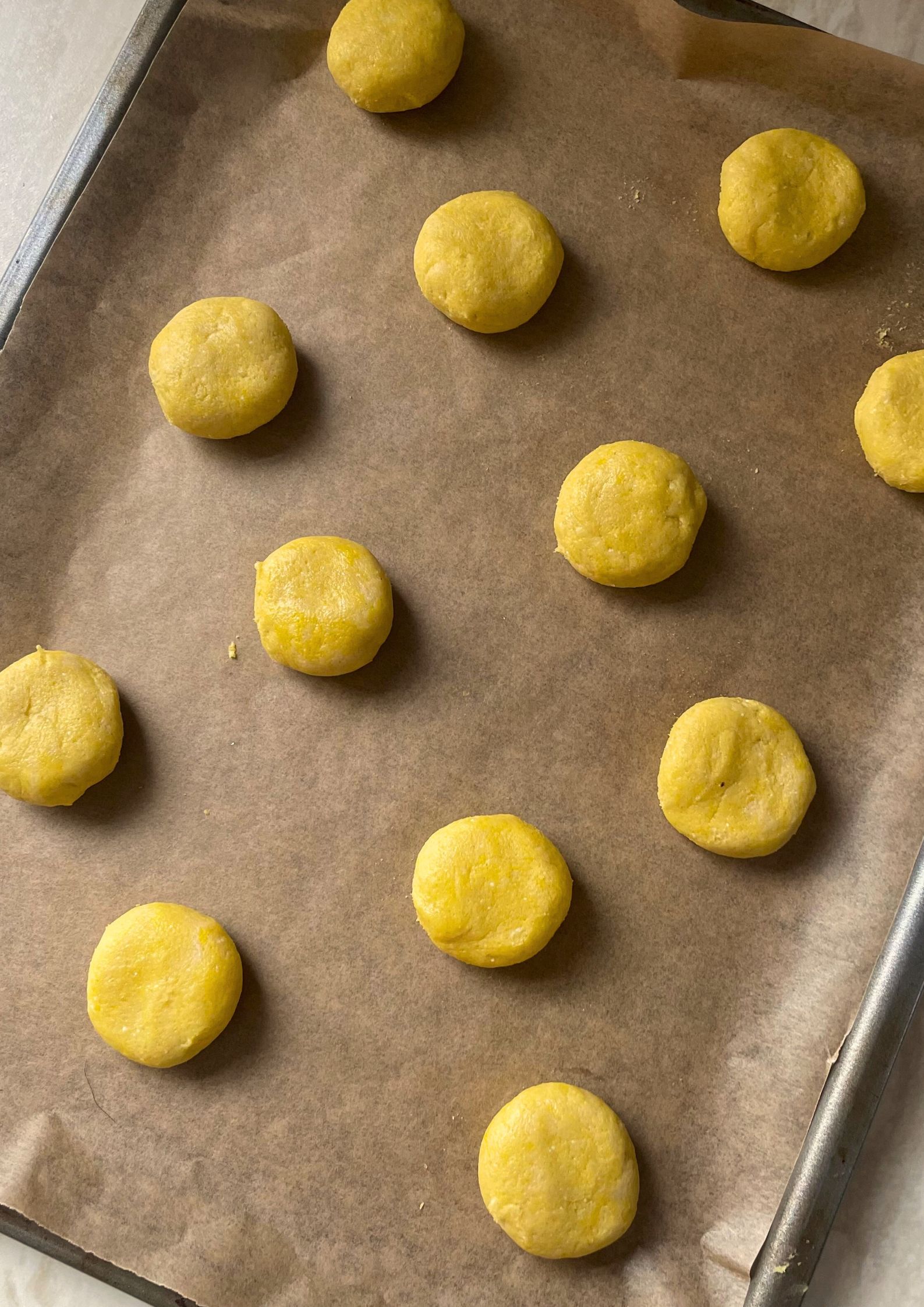 Raw cookie dough balls spaced apart on a baking tray ready to be baked